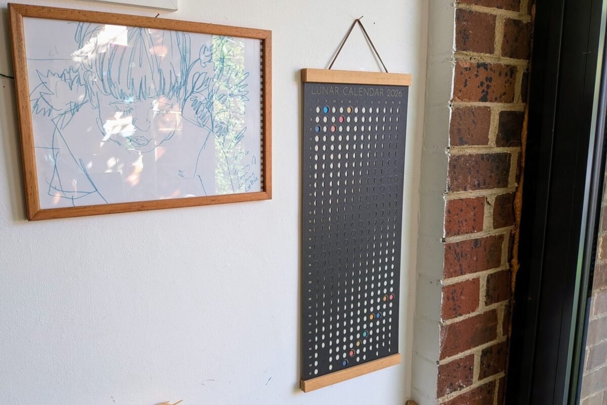 Moonatics | Lunar Calendar 2026 Shadow Edition Moon Phase Lunar Calendar – Shadow Edition hanging on wall with teak magnetic poster frame, modern minimalist home décor.