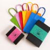 Two Moonatics Eco Potion Kits beside a selection of colourful paper party bags in blue, orange, yellow, red, pink and green, showing a plastic-free party bag alternative for children's celebrations.