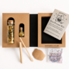 Open mini Moonatics Eco Potion Kit with two glass potion bottles, illustrated instruction booklet and wooden stirring stick, presented in a plastic-free cardboard gift box.