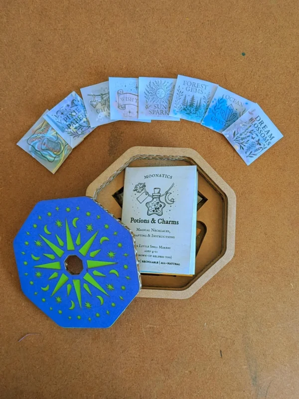 necklace_kit and mixins Open Potion & Charms Necklace Kit showing the illustrated instruction booklet, decorative gift box lid and potion ingredient packets arranged around the box.