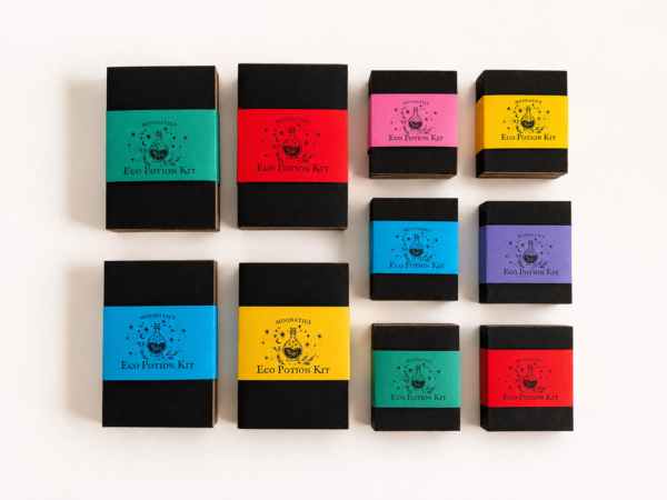 Collection of Moonatics Eco Potion Kits in black cardboard boxes with colourful paper belly bands in turquoise, red, pink, yellow, blue and purple, arranged neatly on a white background.