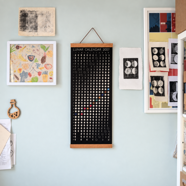 lunar-calendar-2027-artist-studio-wall Moonatics 2027 lunar calendar displayed on a pale green artist studio wall