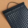 lunar-calendar-2027-black-wooden-hanger-close-up Close-up of the Moonatics 2027 lunar calendar with a black wooden hanger