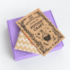 moonatics alchemist eco potion kit - closed box with booklet on top Purple Alchemist Eco Potion Kit gift box with illustrated Potion Craft guide and kraft envelope.