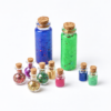 moonatics alchemist eco potion kit - coloured bottles freestanding Corked glass bottles containing blue and green powders, colourful eco glitter and smaller mica pigments.