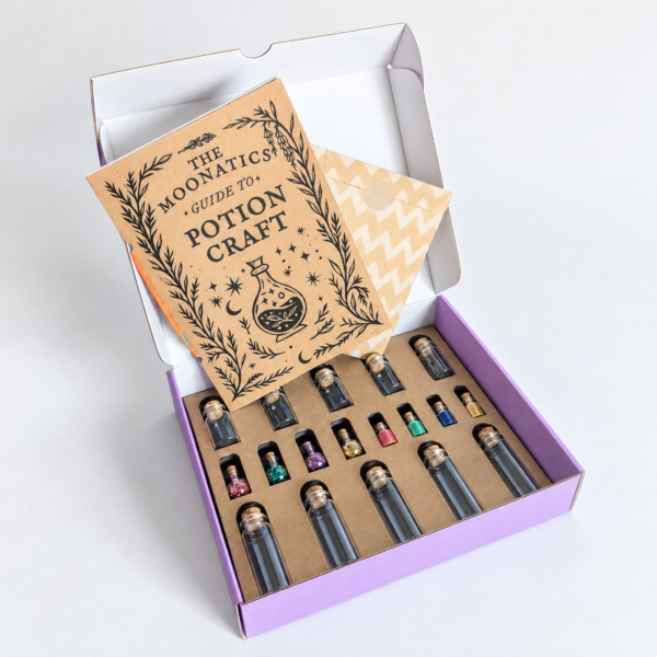 moonatics alchemist eco potion kit - open box Open purple Alchemist Eco Potion Kit showing the craft guide and glass potion bottles in a kraft card tray.